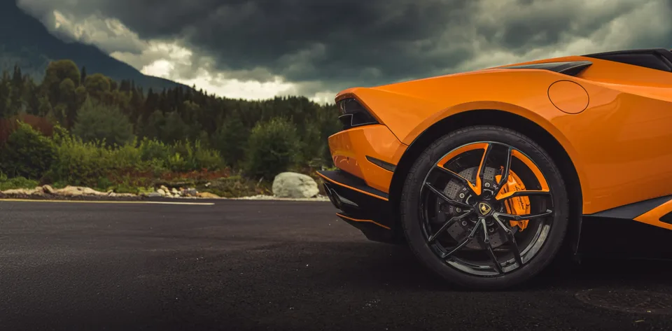 Orange Lamborghini Huracán Spyder, rear wheel and orange brake caliper, under a stormy sky