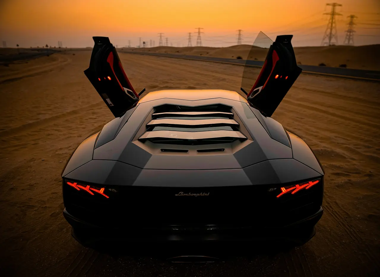 Lamborghini with its doors raised in the desert at sunset